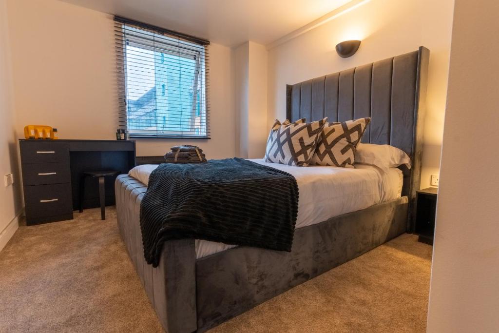 a bedroom with a large bed with a wooden headboard at JPG Theatre Suite - High Floor MCR Luxe Apartment w Balcony Canal Views in Manchester