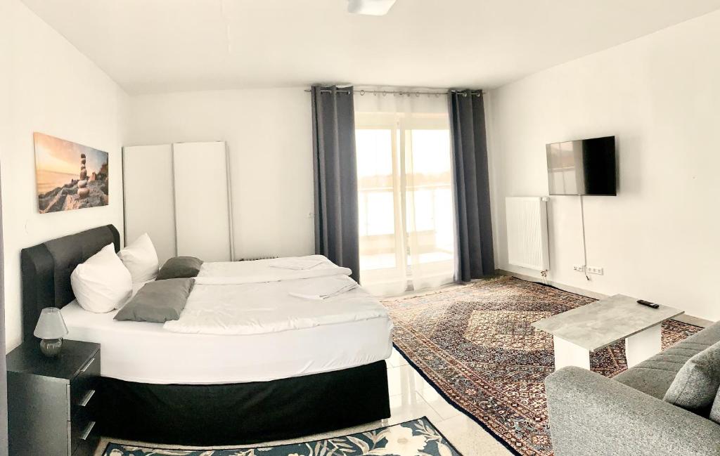a white bedroom with a bed and a couch at Pent - Aparthotel Crailsheim in Crailsheim
