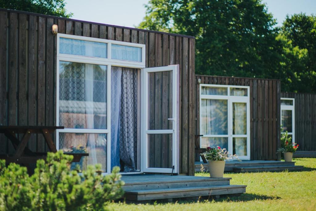 a tiny house with a porch and two windows at SaulesKempings in Mērsrags