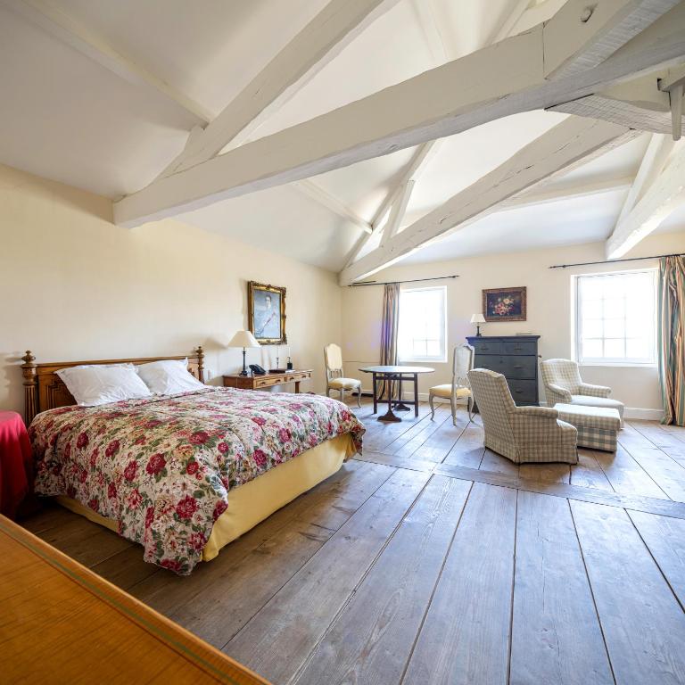 a bedroom with a bed and a desk and chairs at Château du Tertre in Arsac