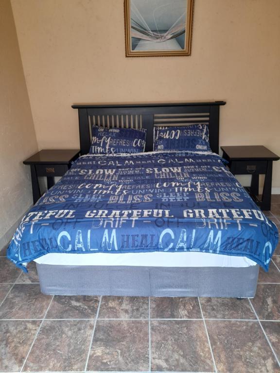 a bed with a blue comforter and pillows on it at Cozy guesthouse springs in Springs