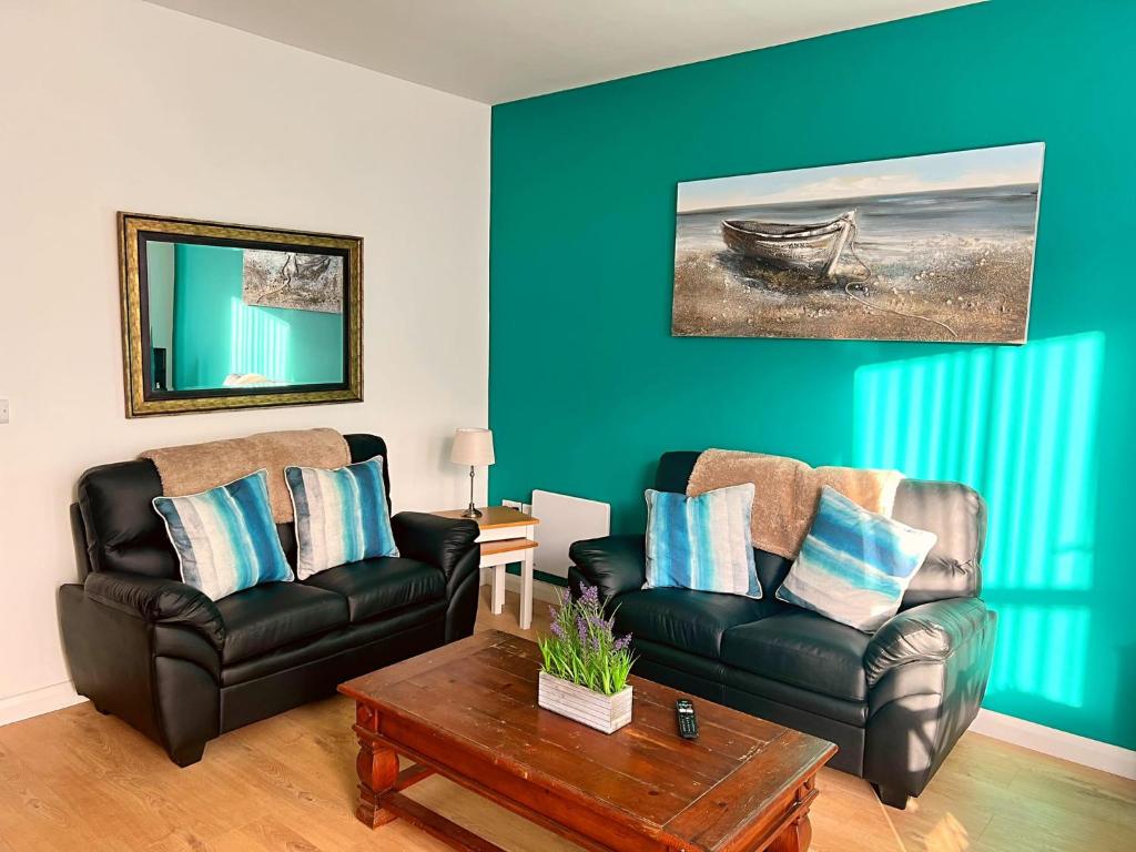 a living room with two leather chairs and a table at Bangor Central Apartments in Bangor