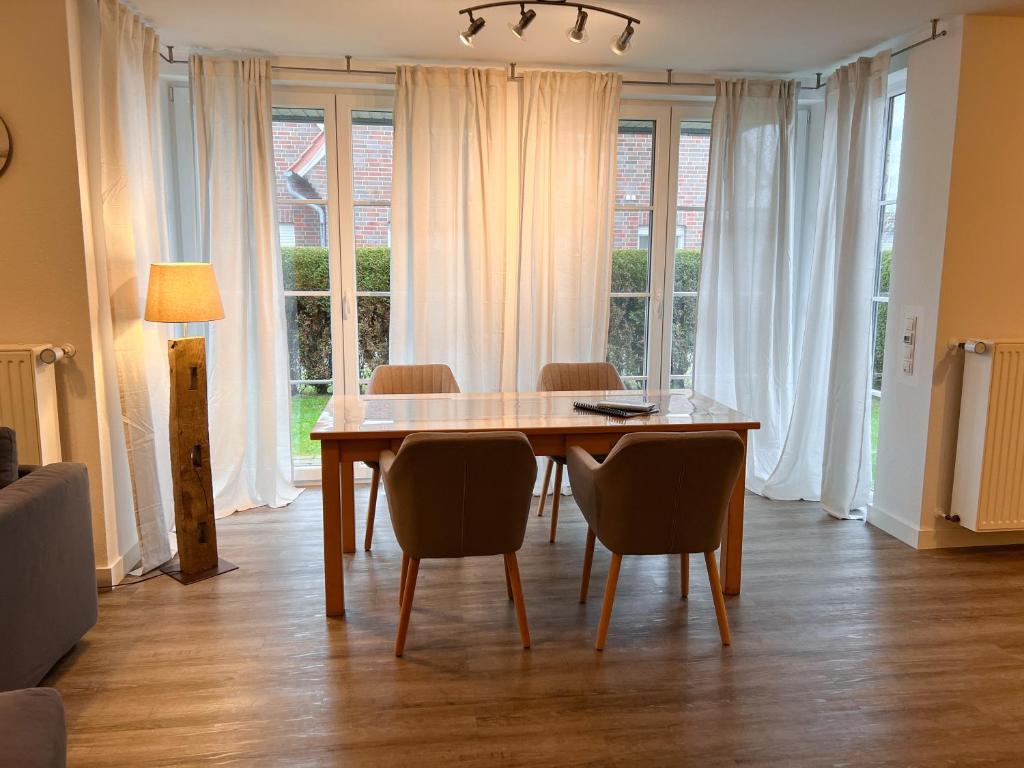 een eetkamer met een tafel, stoelen en ramen bij "Deichmöwe" im Möwennest Greetsiel in Krummhörn