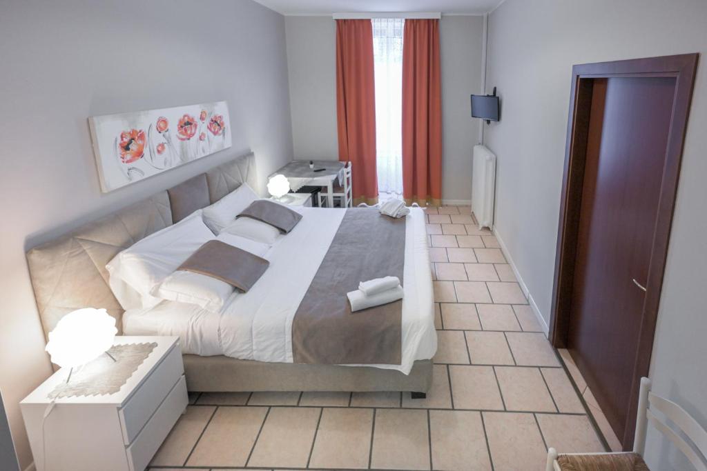 um quarto com uma cama grande com lençóis brancos e almofadas em Affittacamere Berzi em Trieste