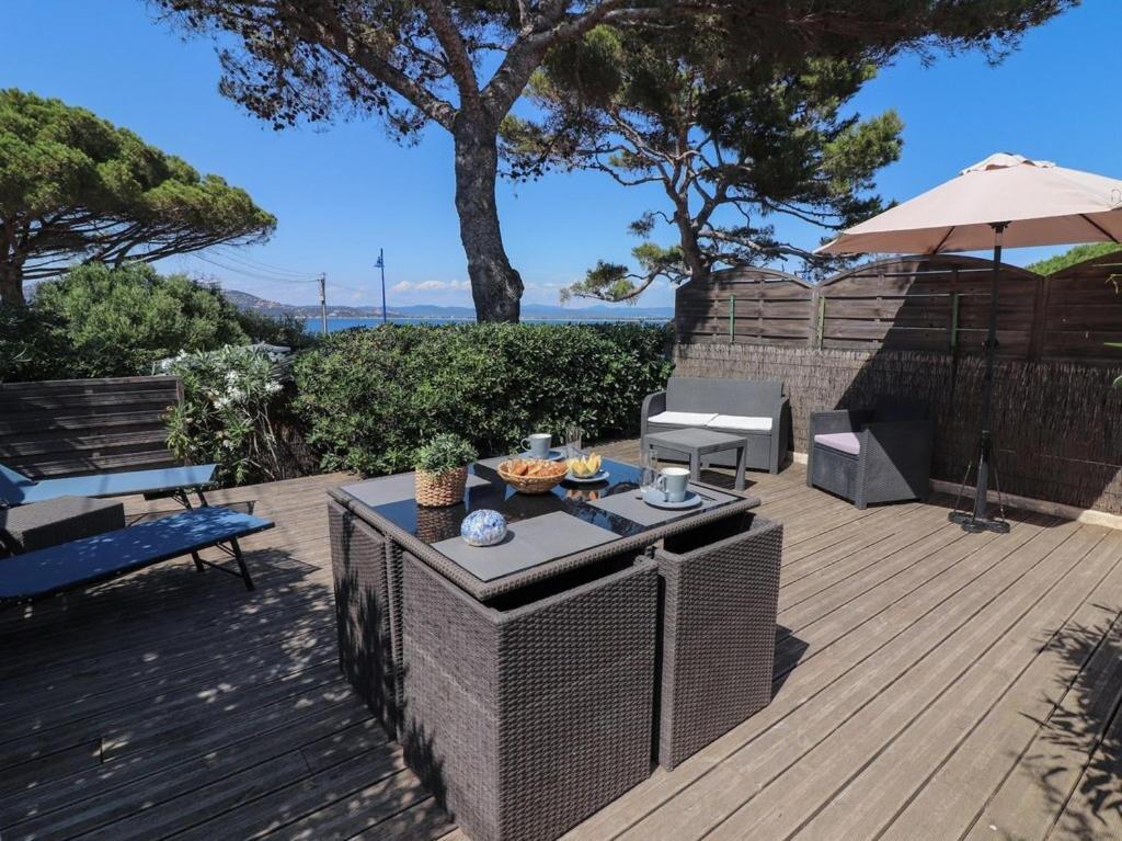une terrasse en bois avec une table et un parasol dans l'établissement Le Bastidon, charmant studio 2 pers avec vue mer, idéalement situé, à Hyères