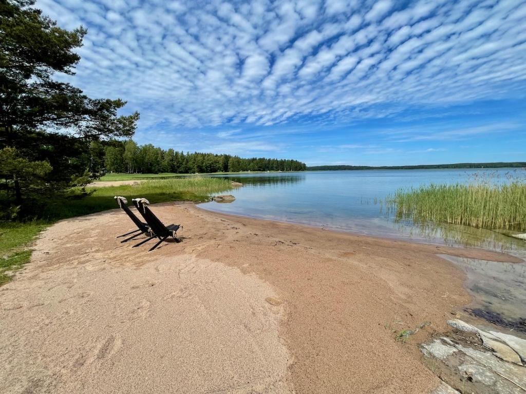 a bench sitting on a beach next to a body of water at Villa Mustikka in Ekenäs
