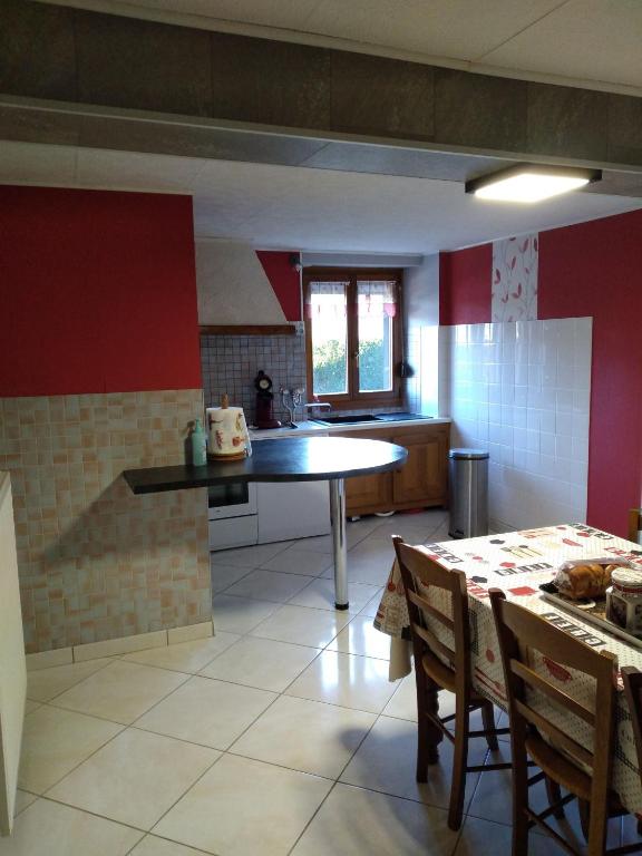 a kitchen with red walls and a table and chairs at gite chez Maise in Le Val-dʼAjol