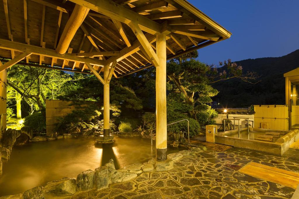 une pergola en bois avec une masse d'eau dans l'établissement Ryokan Fushioukaku, à Ikeda