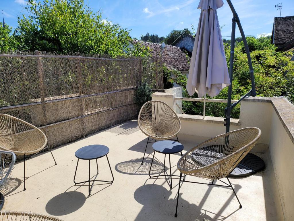une terrasse avec 3 chaises et un parasol dans l'établissement L'Escapade 3 étoiles, à Champagne-sur-Seine