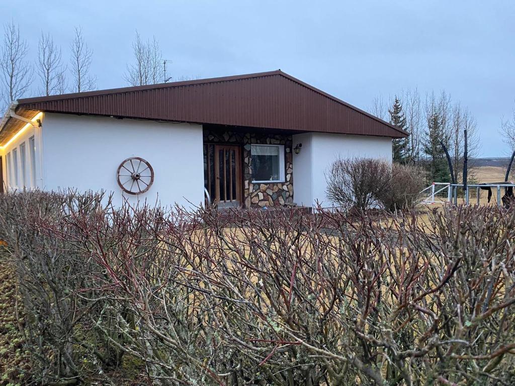 Una casa blanca con un reloj al costado. en Golden Circle private Farmhouse with hot tub, en Selfoss