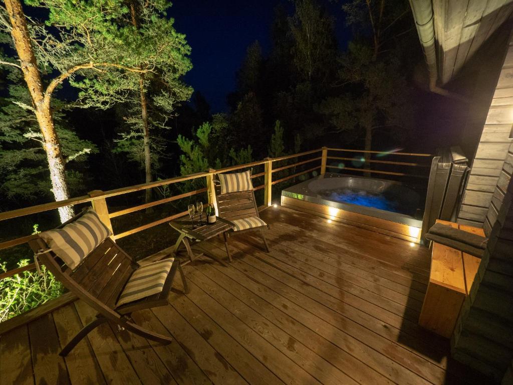 a deck with two chairs and a hot tub at night at Villa Mustikka in Ekenäs