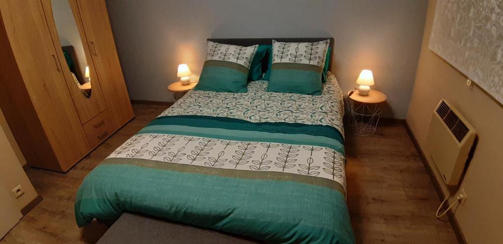 een slaapkamer met een groot bed met groene en witte lakens bij Petit appartement cosy in Bastenaken