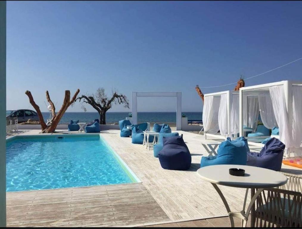 una piscina con sillas azules, una mesa y el océano en Къща за Гости в Созополи, en Sozopoli