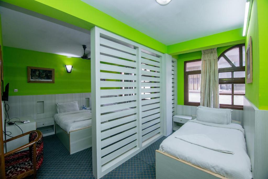 a bedroom with green walls and a bed and a desk at Hotel Pomelo House Inn in Kathmandu