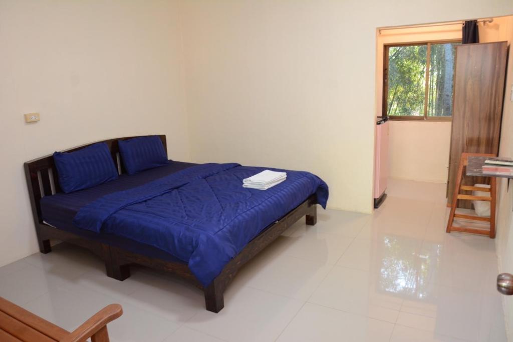 1 dormitorio con cama con sábanas azules y ventana en โคบาล ห้องพักรายวัน, en Chom Thong