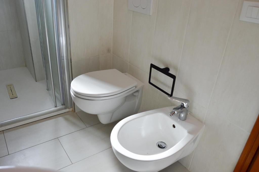 a white bathroom with a toilet and a sink at Onda Su Onda Appartamenti in Seccheto