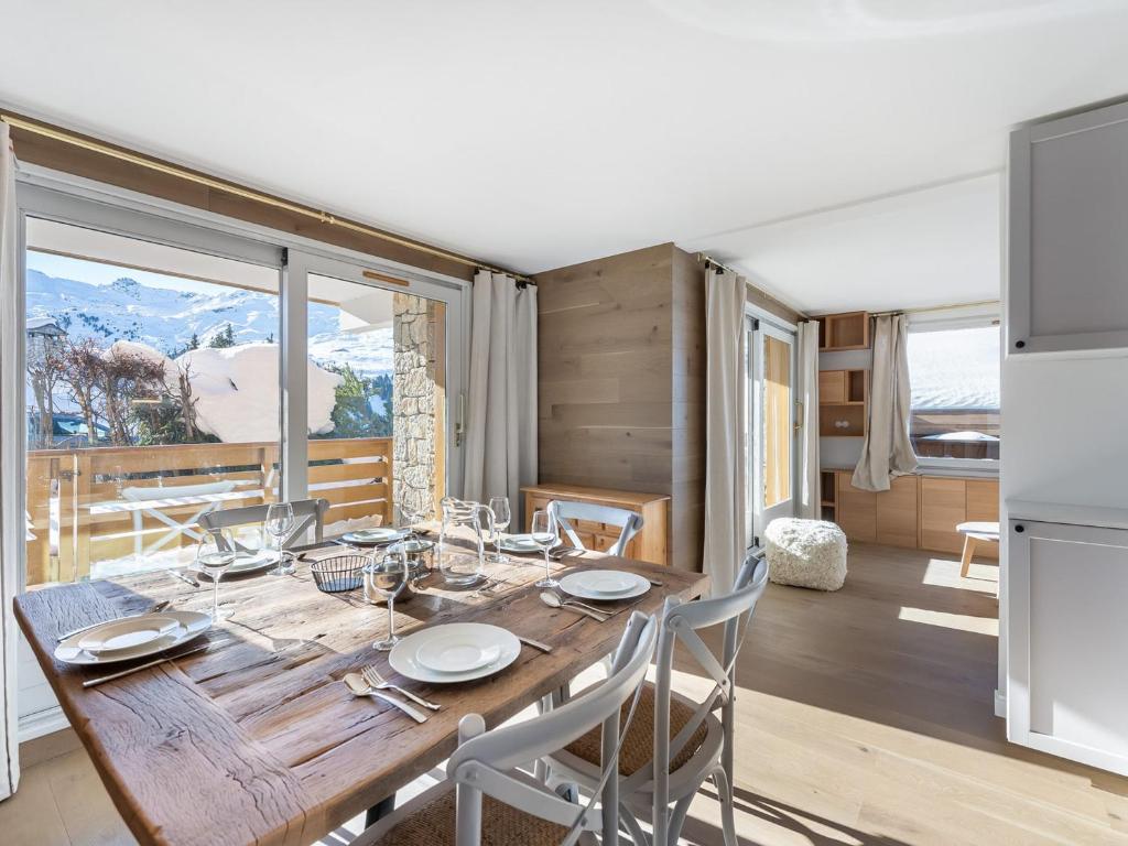 une salle à manger avec une table en bois et une grande fenêtre dans l'établissement Appartement Cozy Pied des Pistes avec Terrasse – Méribel, les 3 Vallées - FR-1-565-59, à Les Allues