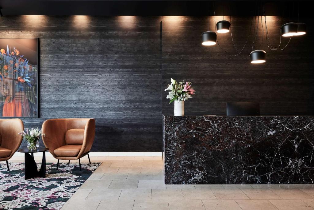 un vestíbulo con 2 sillas y una mesa con flores en Adina Apartment Hotel Melbourne Flinders Street, en Melbourne