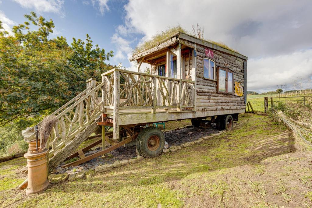 2x Double Bed - Glamping Wagon Dalby Forest في سكرابورو: شاحنة خشبية قديمة مع منزل في الخلف