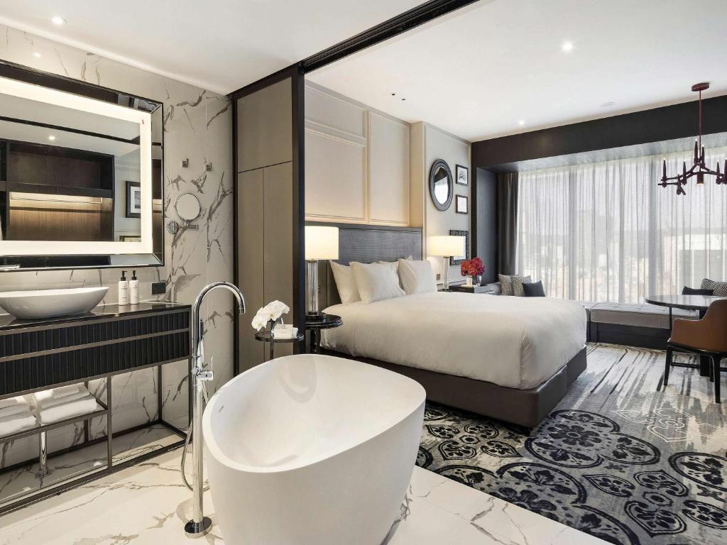 Sofitel Adelaide في أديلايد: غرفة في الفندق مع سرير وحوض استحمام