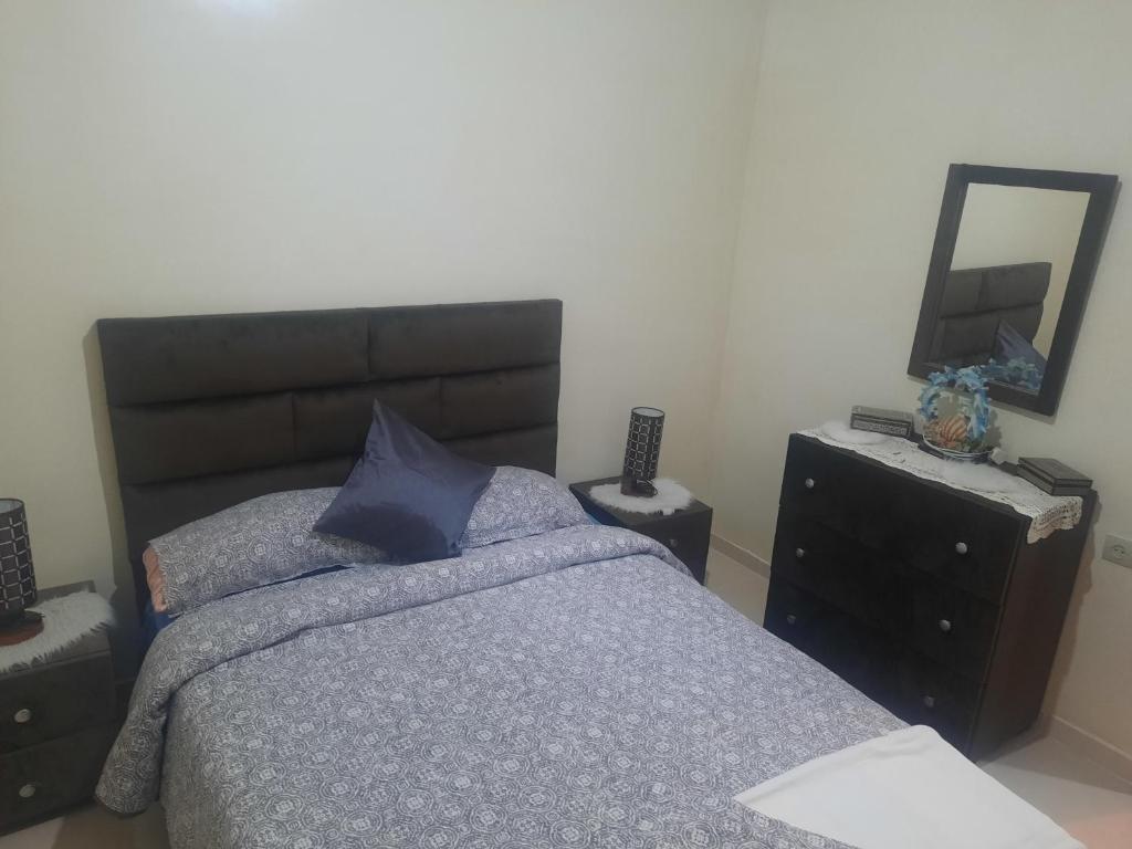 1 dormitorio con cama, espejo y tocador en راحتي en Tánger