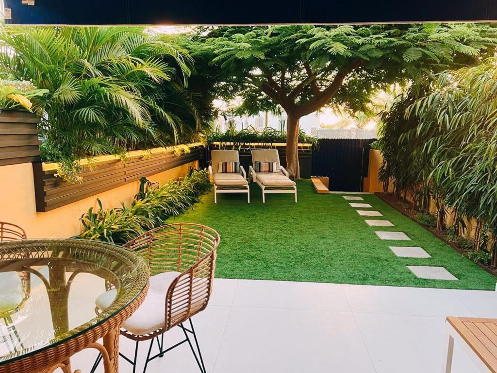 a patio with chairs and a tree and grass at Meloneras Garden Suite in Meloneras