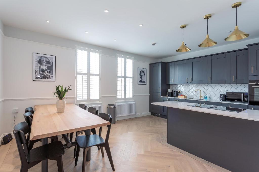 a kitchen with a wooden table and black cabinets at The Stanley Maisonette in Teddington
