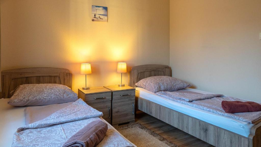 two twin beds in a room with two lamps on them at Király Panzió in Tolcsva