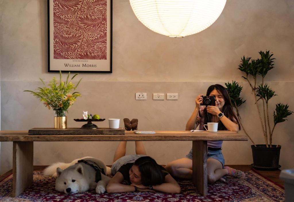 平和村的住宿－The Peaceful Village 花蓮小和民宿 2090，两个女孩和狗一起躺在地板上的桌子下