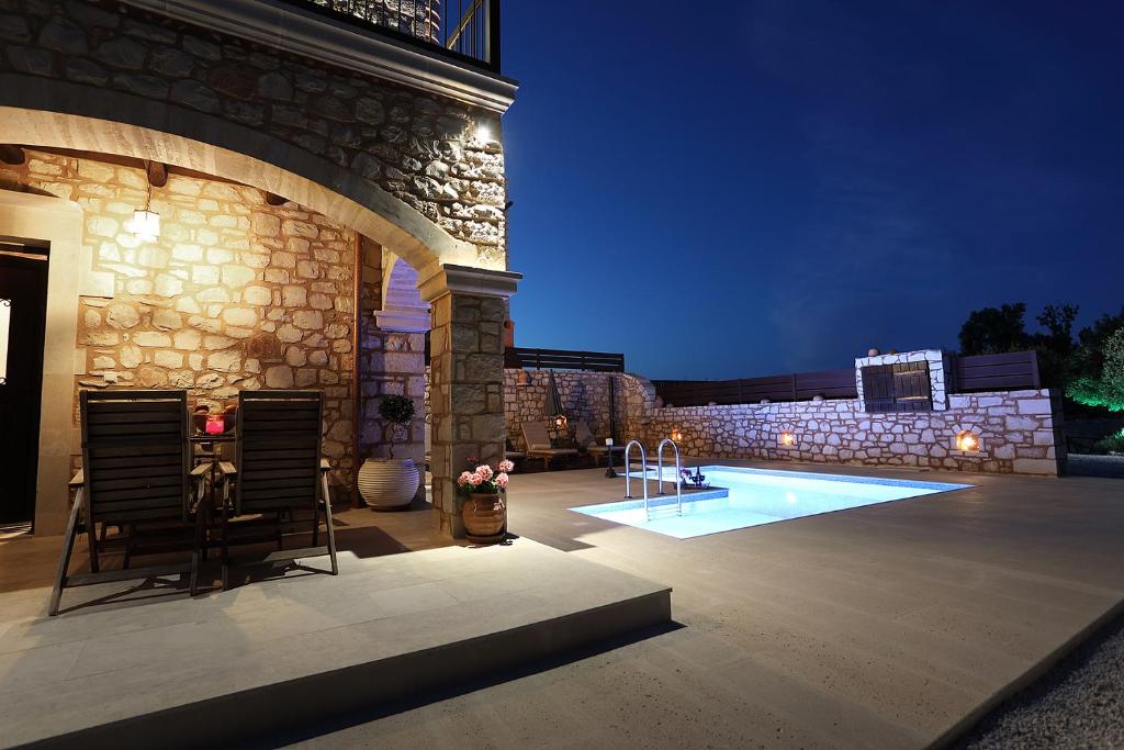 un patio con sillas y una piscina por la noche en Deluxe Villa LaCasa 2 with Private Pool en Roumelí