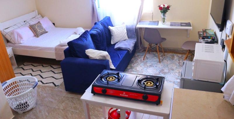 ein Wohnzimmer mit einem blauen Sofa und einem Bett in der Unterkunft Lux Suites Mtwapa Studio Apartment-2 in Mtwapa