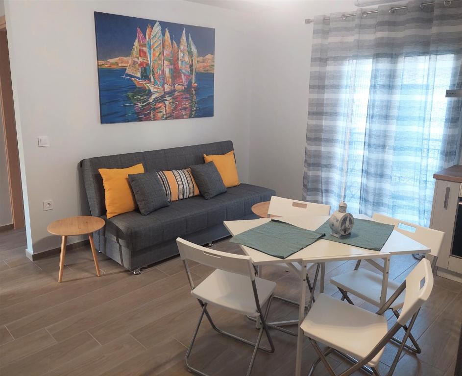 uma sala de estar com um sofá, uma mesa e cadeiras em La Casita a brand new apartment in the center em Argostoli