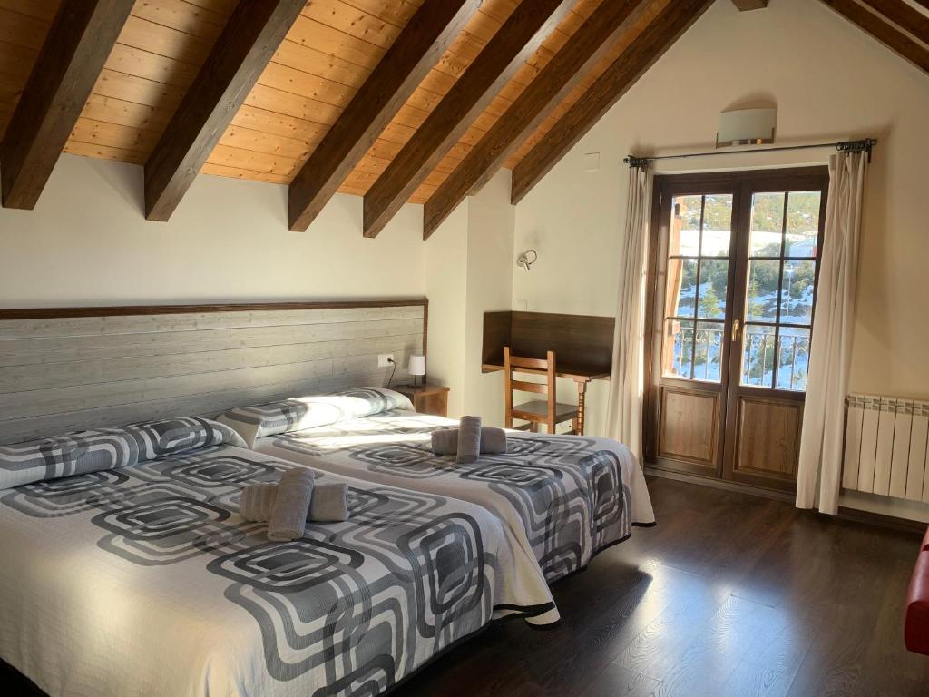 a bedroom with two beds and a large window at Casa Taconera in Ansó