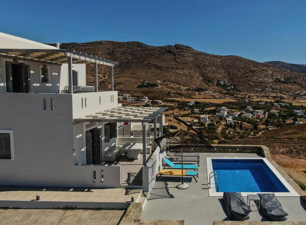 a white house with a swimming pool and a mountain at Antigoni Villas in Gavrio