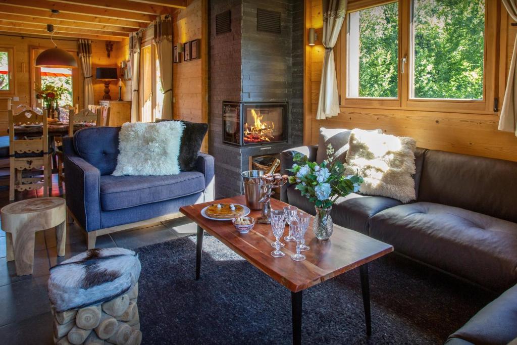 a living room with couches and a table and a fireplace at Lodge le Chevreuil - OVO Network in Le Grand-Bornand