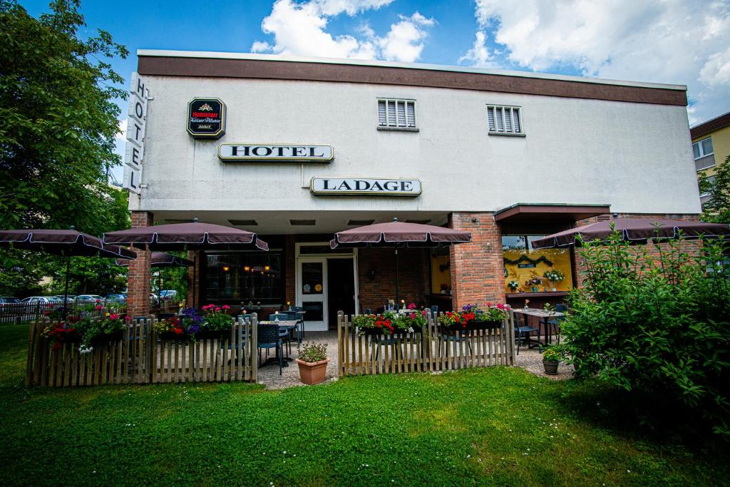 a hotel with tables and umbrellas in front of it at Hotel Ladage in Frankfurt/Main