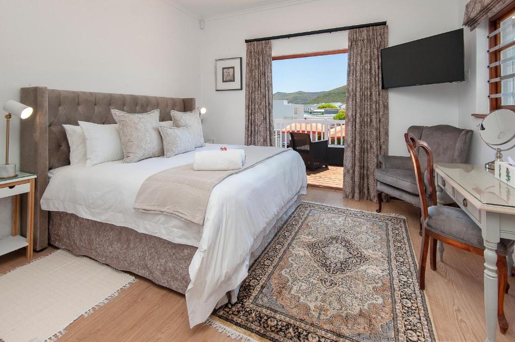 a bedroom with a bed and a desk and a window at Villa Venusta Luxury Guesthouse - Solar Power in Hermanus