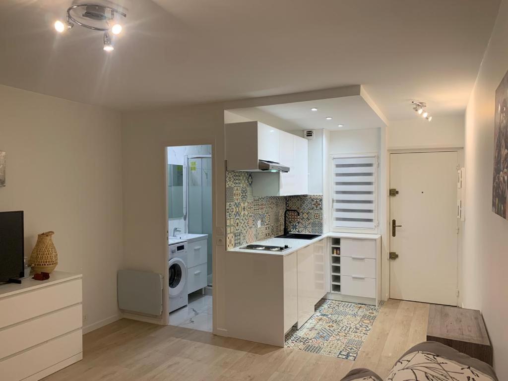 cocina con armarios blancos, lavadora y secadora en Studio en hypercentre refait à neuf avec une belle terrasse!, en Cabourg
