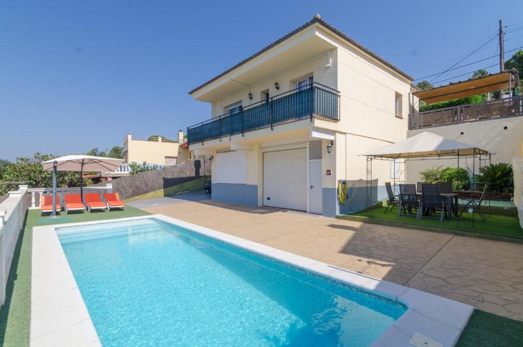 ein Haus mit einem Pool vor einem Haus in der Unterkunft Club Villamar - Santelmo in Lloret de Mar