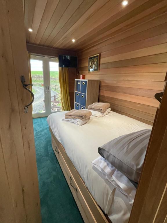 a bedroom with a bed in a room with wooden walls at East Learmouth Lakeside Lodges - Larch Lodge in Cornhill-on-tweed