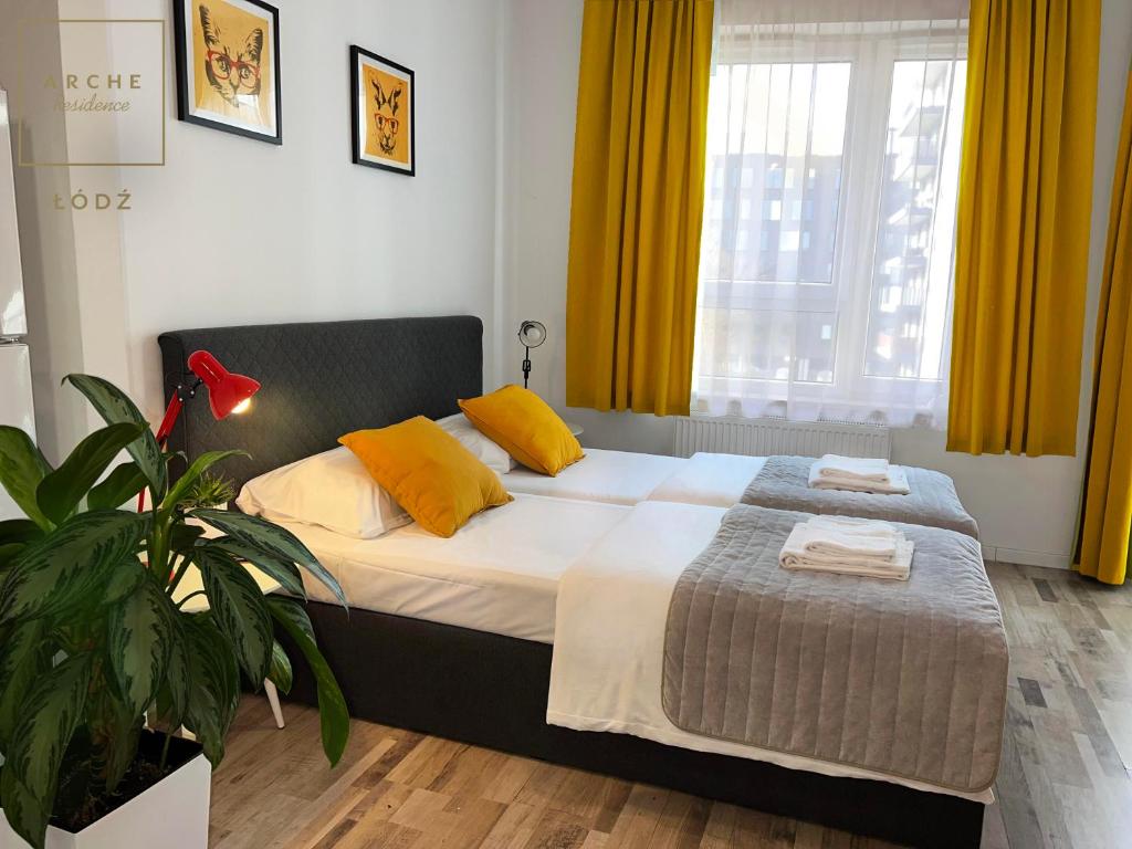 um quarto com uma cama com cortinas amarelas e uma planta em Arche Residence Łódź em Łódź