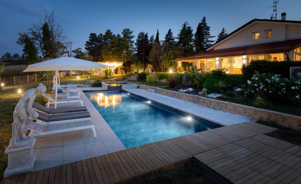 una piscina con sillas y una sombrilla junto a una casa en Villa Fai Bei Sogni-Green Bed & Breakfast, en Coriano