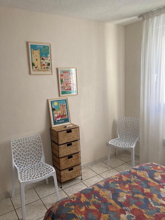 sypialnia z 2 krzesłami, łóżkiem i komodą w obiekcie Appartement proche des halles w mieście Narbona