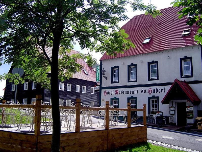 un edificio con mesas y sillas frente a un edificio en Hotel Svaty Hubert, en Boží Dar