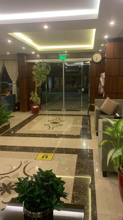 eine Lobby mit Pflanzen und einer Uhr in einem Gebäude in der Unterkunft دانة الشرق للشقق المخدومة in Khobar