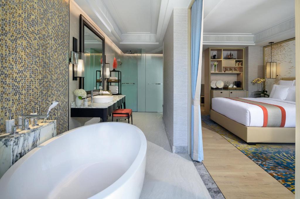 a bathroom with a tub and a bedroom with a bed at InterContinental Phuket Resort by IHG in Kamala Beach