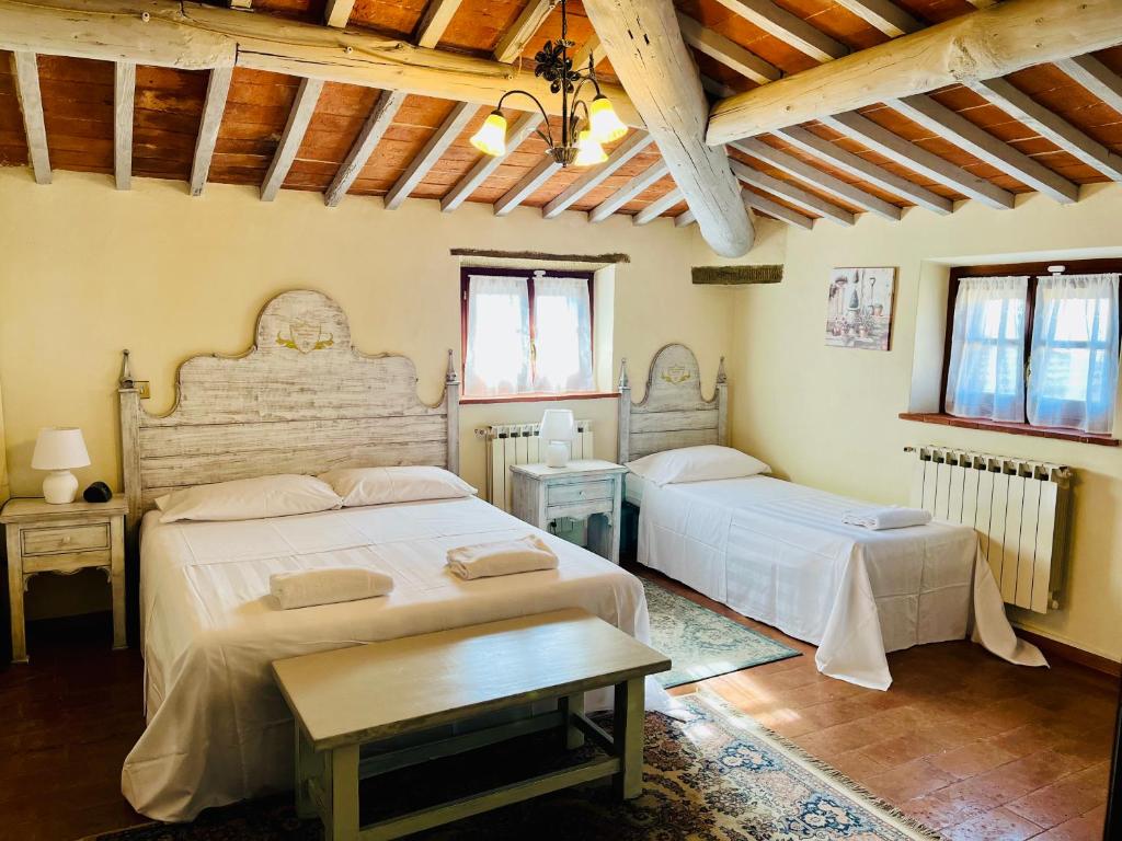sypialnia z 2 łóżkami i drewnianym sufitem w obiekcie Villa Schiatti w mieście Cortona