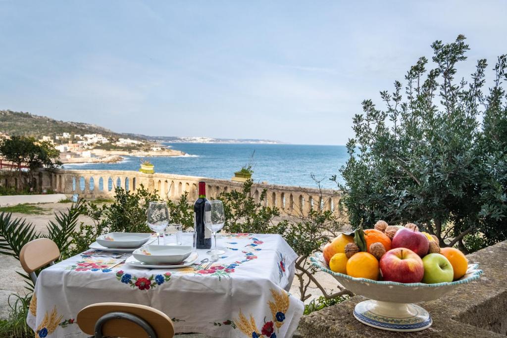 een tafel met een fruitschaal en een fles wijn bij Casa sul Mare - Tricase in Marina Porto
