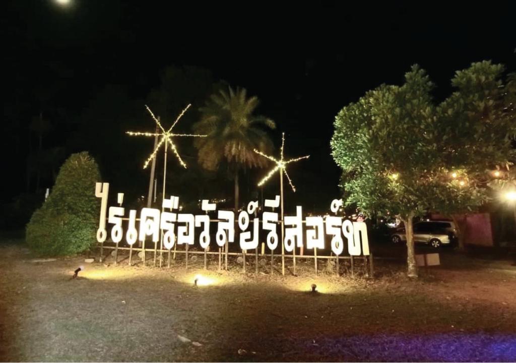 Una señal encendida en un parque por la noche en Raikhruewan Resort Muaklek ไร่เครือวัลย์ รีสอร์ท, en Muak Lek