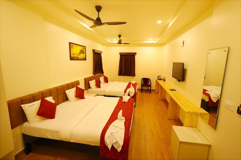 a hotel room with two beds and a mirror at Hotel Vijaya Grand in Srikalahasti